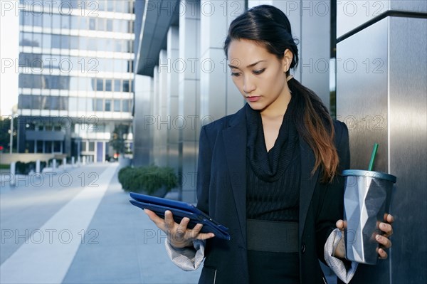 Mixed race businesswoman using tablet computer on city street