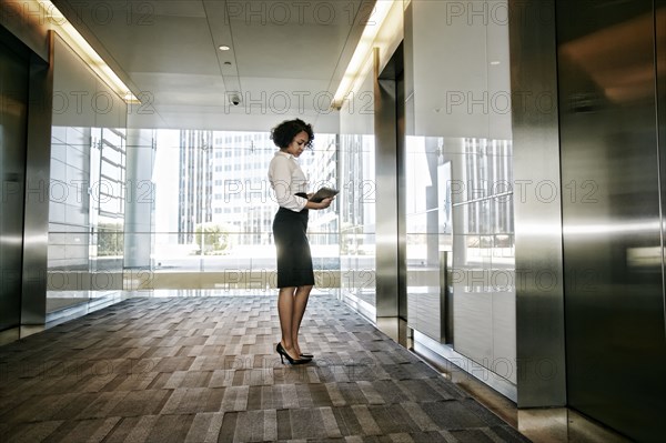 Mixed race businesswoman using tablet computer in lobby