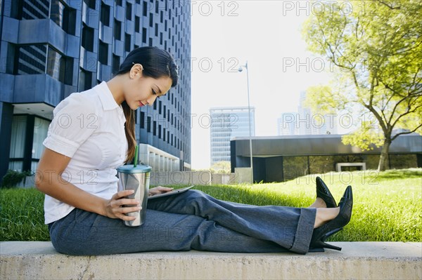 Mixed race businesswoman using tablet computer in city