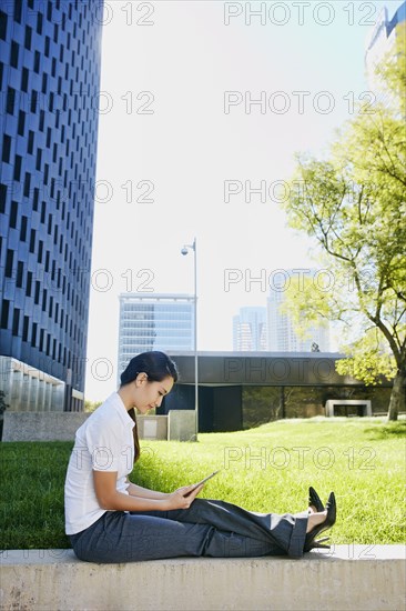 Mixed race businesswoman using tablet computer in city