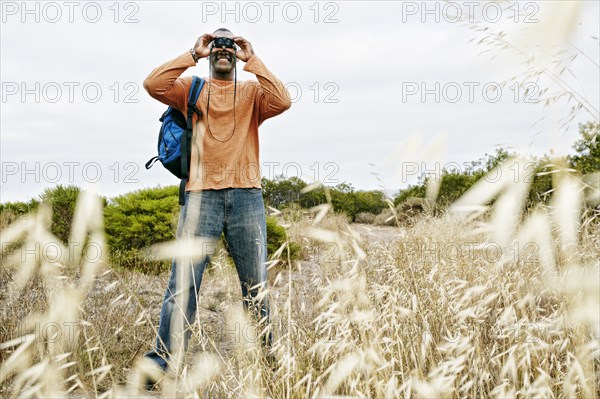 Black man hiking on rural hillside