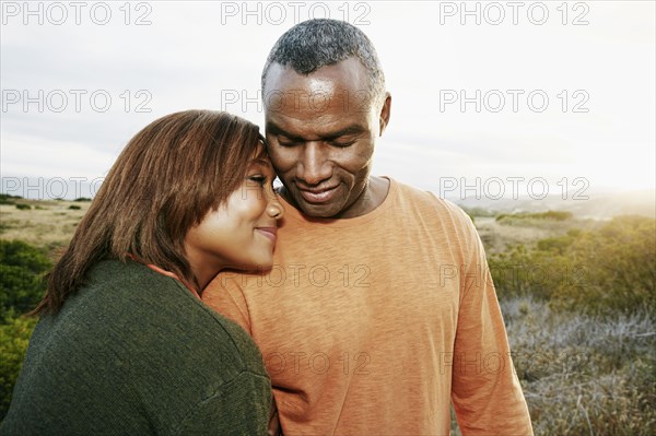 Black couple hugging on rural hillside