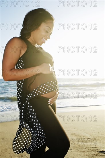 Pregnant woman holding her belly on beach