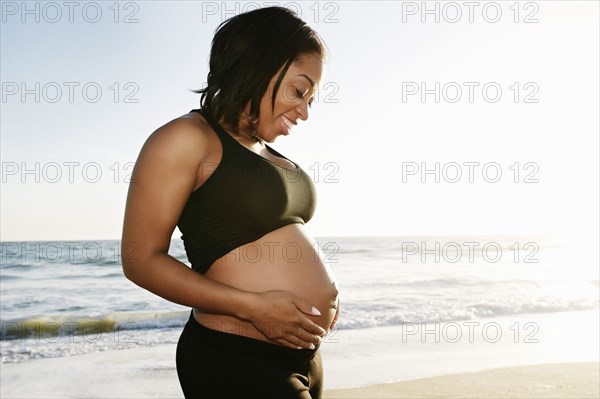 Pregnant woman holding her belly on beach