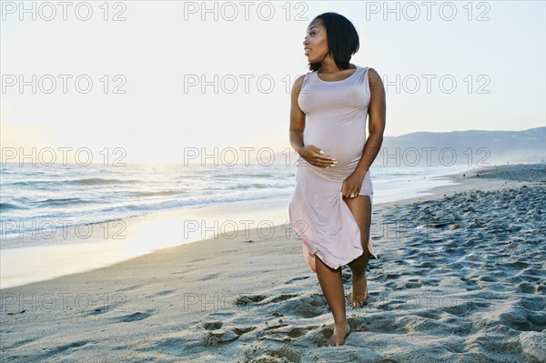 Pregnant woman holding her belly on beach