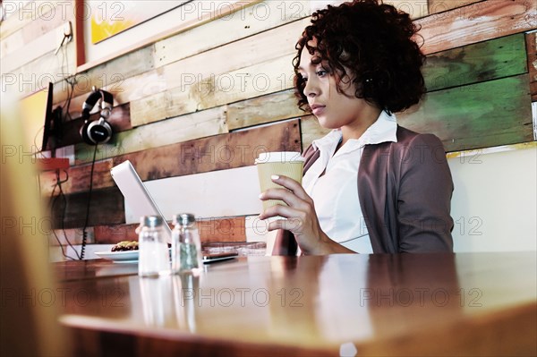 Mixed race businesswoman using laptop in cafe