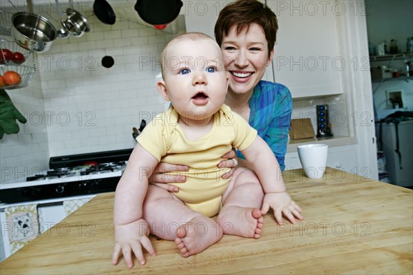 Caucasian mother and baby relaxing in kitchen