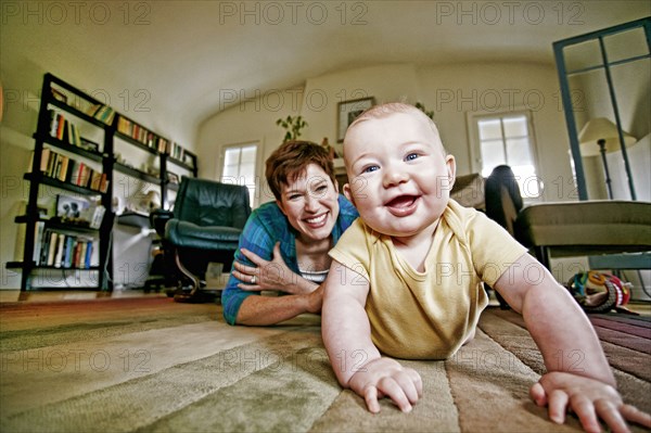 Caucasian mother and baby playing on living room floor