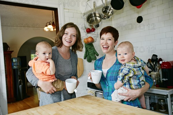 Caucasian mothers holding babies in kitchen