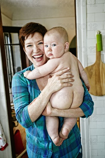 Caucasian mother holding nude baby in bathroom