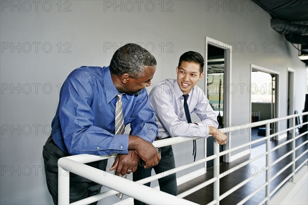 Businessmen talking at railing