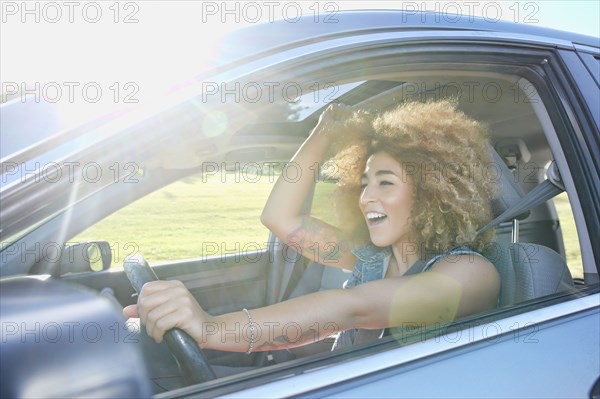 Hispanic woman cheering and driving car