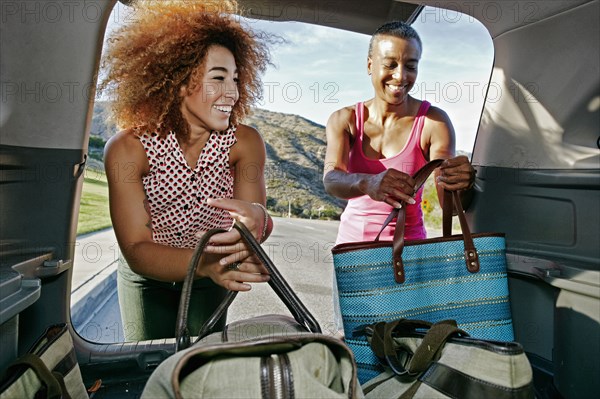Mother and daughter unloading bags from car