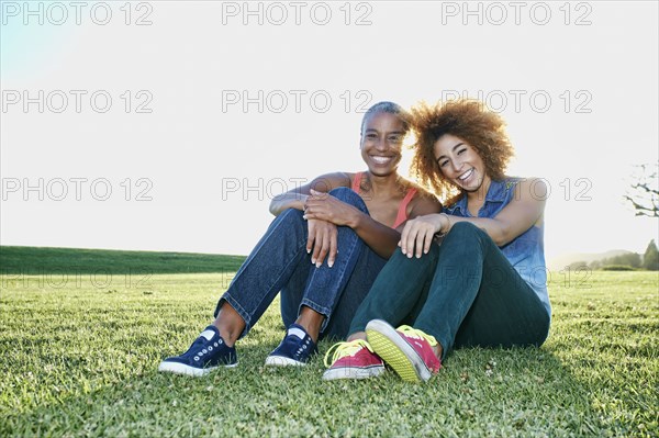 Mother and daughter sitting in field