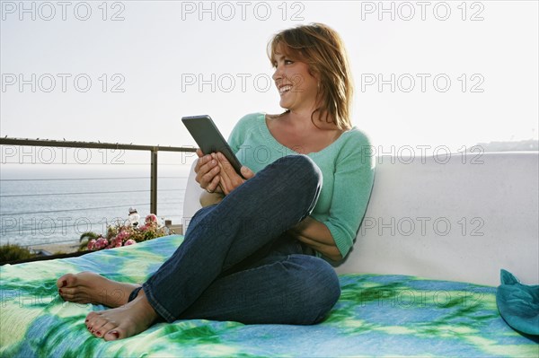 Caucasian woman using digital tablet at waterfront