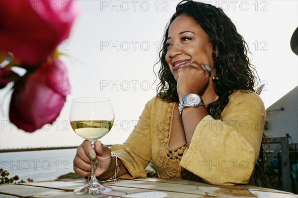 Mixed race woman drinking wine at waterfront