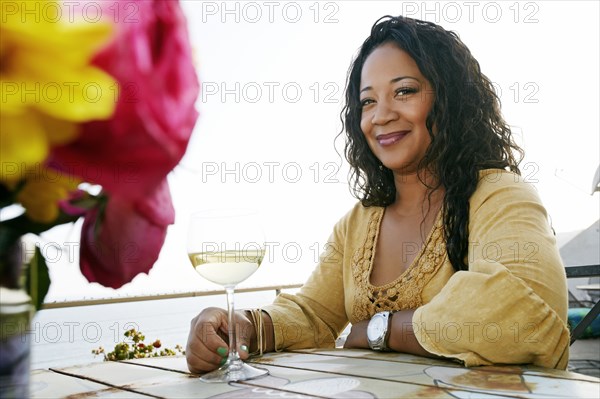 Mixed race woman drinking wine at waterfront