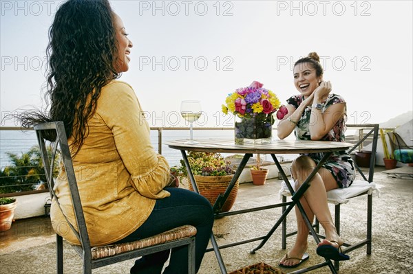 Women drinking wine together at waterfront