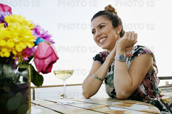 Mixed race woman drinking wine at waterfront