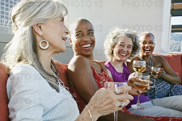 Women drinking wine together on urban rooftop