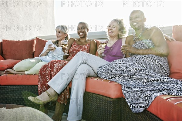 Women drinking wine together on urban rooftop