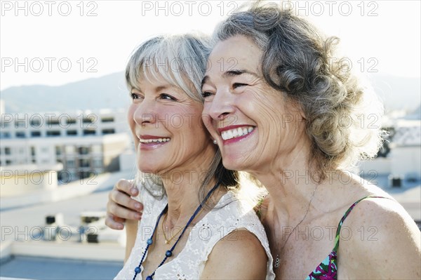 Women smiling together on urban rooftop