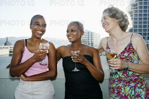 Women drinking wine together on urban rooftop