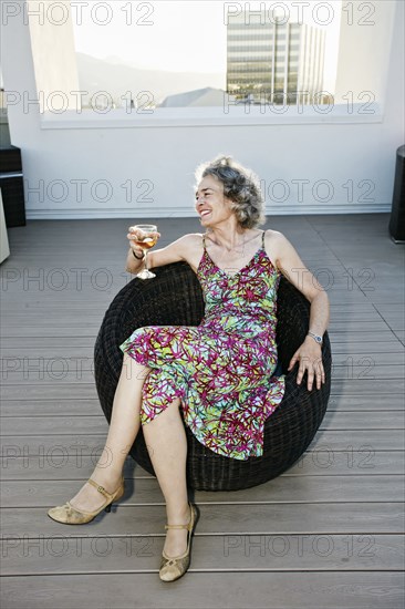 Caucasian woman drinking wine on urban rooftop