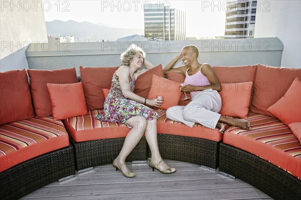 Women drinking wine together on urban rooftop