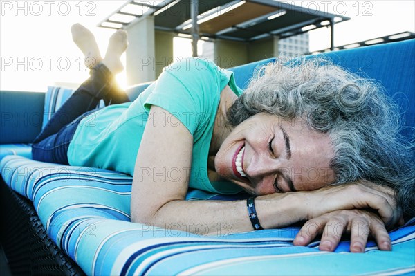 Caucasian woman relaxing on sofa on urban rooftop