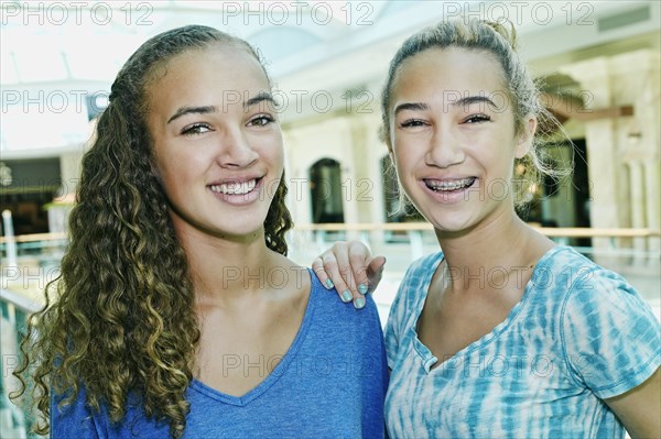 Mixed race teenage girls smiling at shopping mall