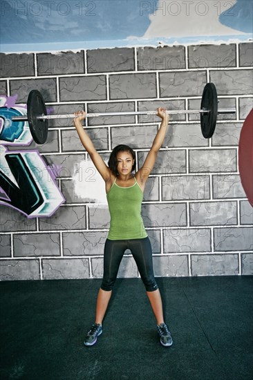 African American woman lifting weights in gym