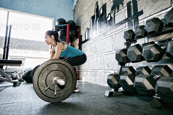 Mixed race woman lifting weights in gym