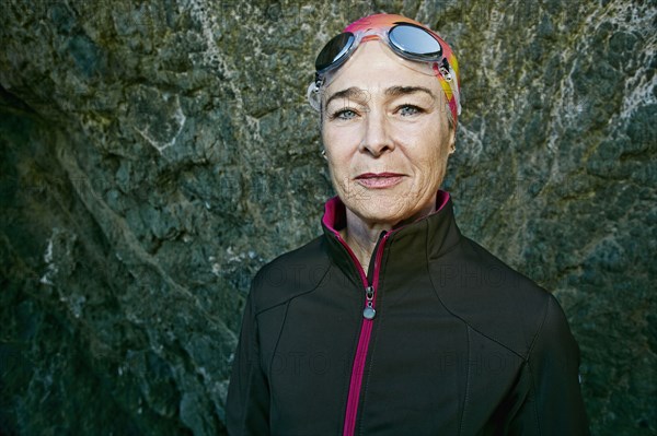 Older Caucasian woman wearing goggles near rock