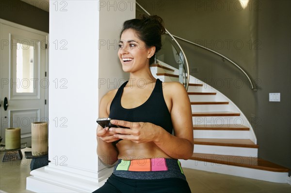 Athletic mixed race woman using cell phone near pillar