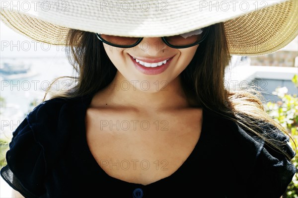 Smiling mixed race woman wearing sunglasses and sun hat