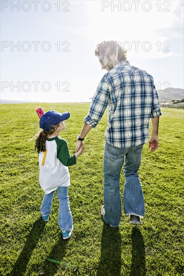 Father and daughter walking in grassy field