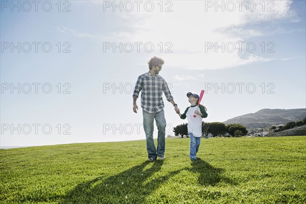 Father and daughter walking in grassy field