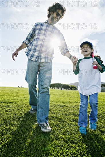 Father and daughter walking in grassy field