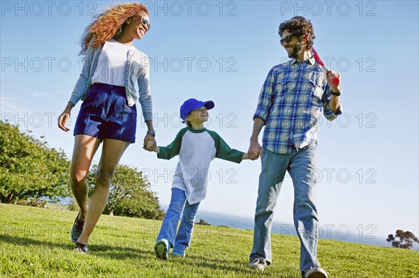 Parents and daughter walking in grassy field