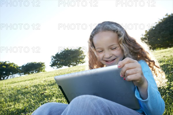 Mixed race girl using digital tablet in field