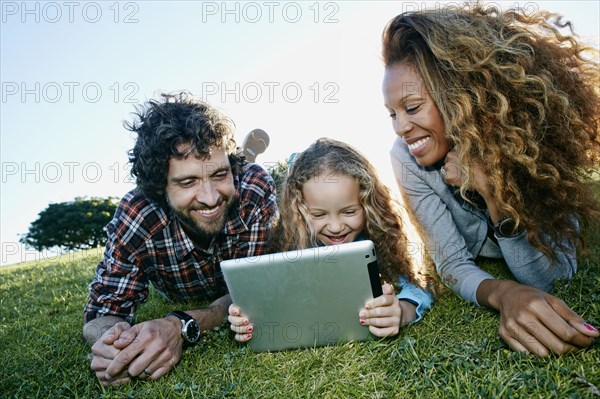Family using digital tablet in grassy field