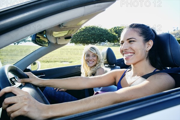 Excited women driving convertible on road trip