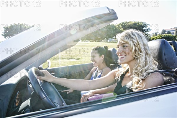 Excited women driving convertible on road trip