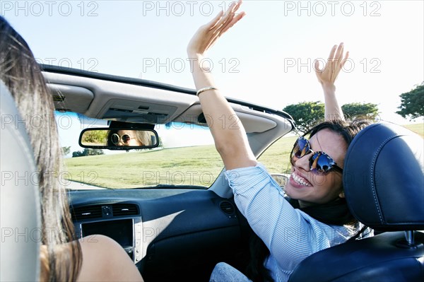 Excited women driving convertible on road trip