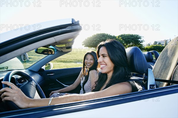 Excited women driving convertible on road trip