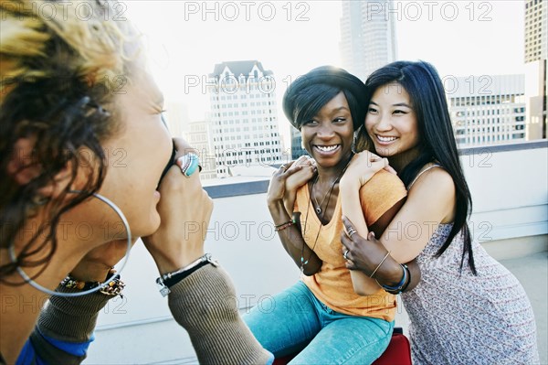 Woman photographing friends on urban rooftop