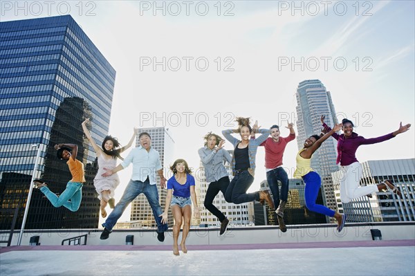 Friends jumping for joy on urban rooftop