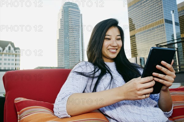 Chinese woman using digital tablet on urban rooftop
