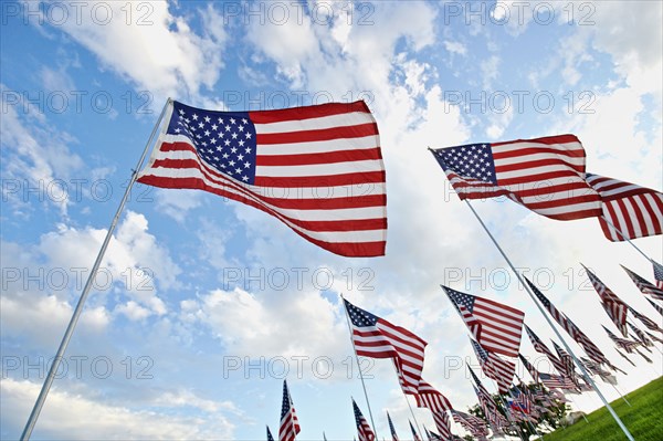 Low angle view of American flags under blue sky